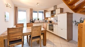 A modern kitchen with a dining area, wooden furniture, and a view of the city.