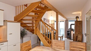 A kitchen with a wooden staircase, a dining table, and chairs.