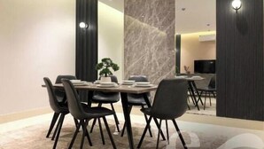 A dining area with a marble wall, a potted plant, and a TV in the background. - Kease Tawun A5-1 Royal Touch XZ16 (Riyadh)
