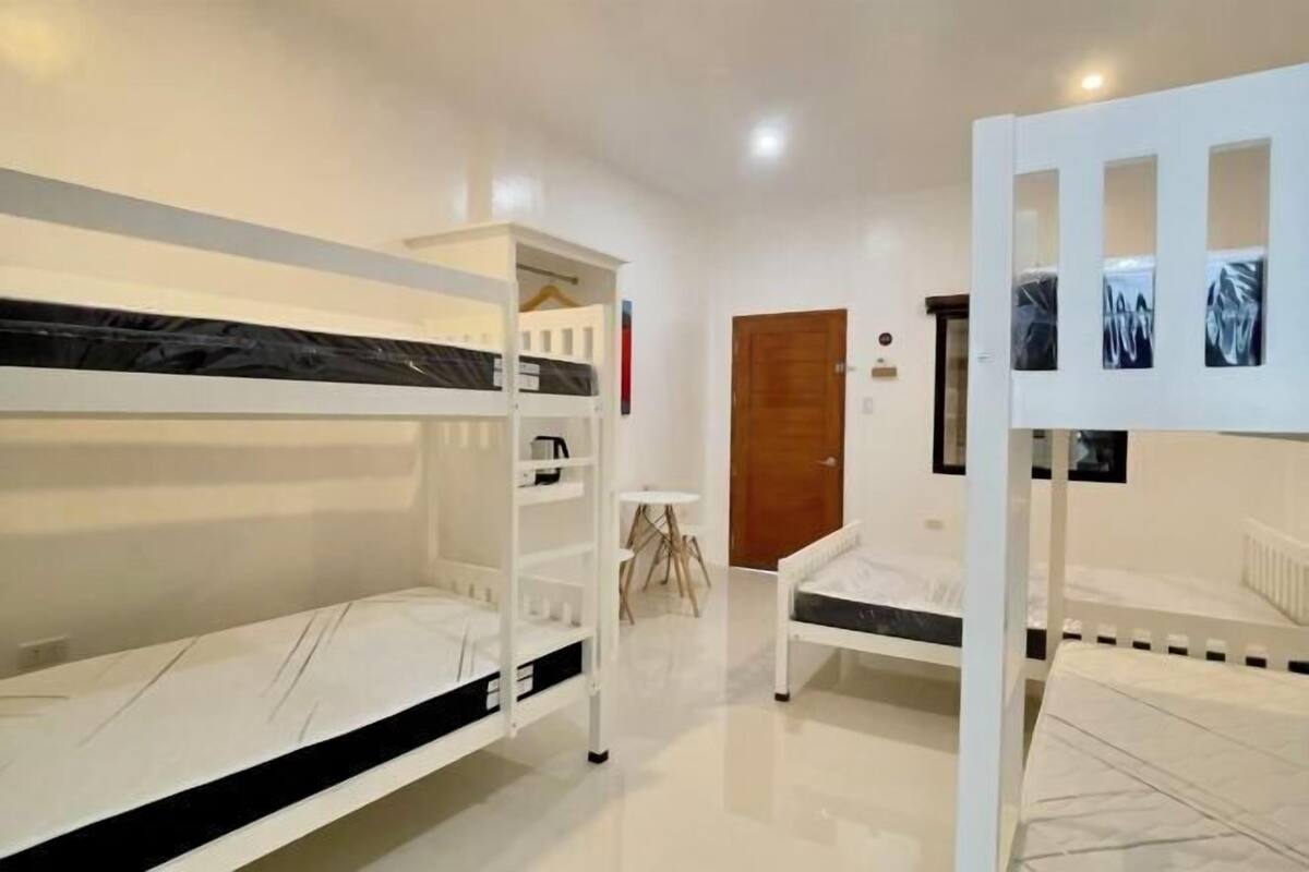 A room with bunk beds, a small table, and a door.