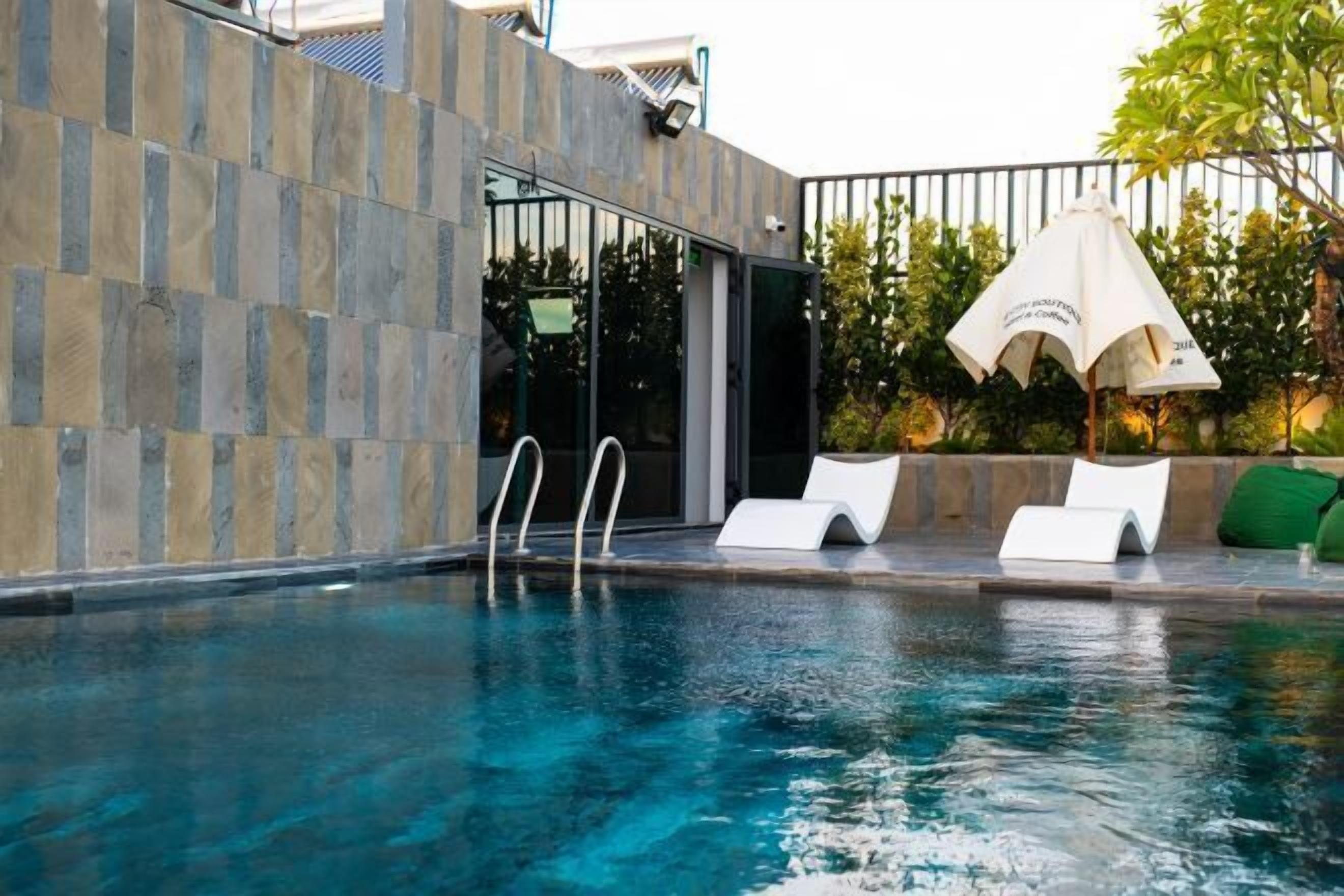 Una piscina con sillas de descanso y una entrada con puerta de cristal.