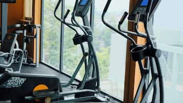 An indoor exercise machine with a digital display, positioned near a window with a view of greenery.