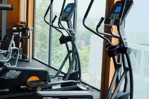 An indoor exercise machine with a digital display, positioned near a window with a view of greenery. - The City Boutique Hotel (Bien Hoa)