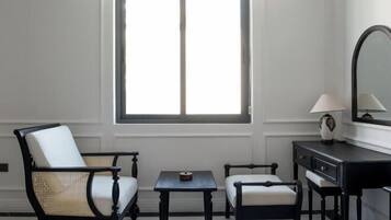 Habitación de hotel con cama, dos sillones, una mesita, cómoda, espejo y ventana.
