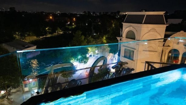 Ein Pool mit Unendlichwirkung und Glasbrüstung, Blick auf eine Stadtlandschaft und ein Gebäude im klassischen Stil.