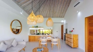 Una sala de estar moderna con un sofá, una mesa de comedor y sillas, una cocina al fondo, y un armario de madera.