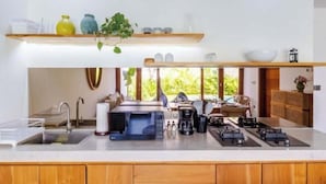 Una cocina moderna con microondas integrado, cafetera y estufa a gas. Hay una ventana que proporciona luz natural y vistas al follaje exterior.