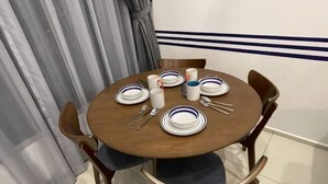 A round wooden dining table with white plates, cutlery, and a candle.