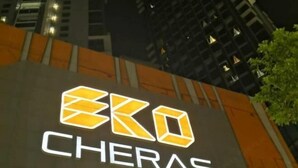 A sign with the logo and name "EKO CHERAS" on a building facade at night.