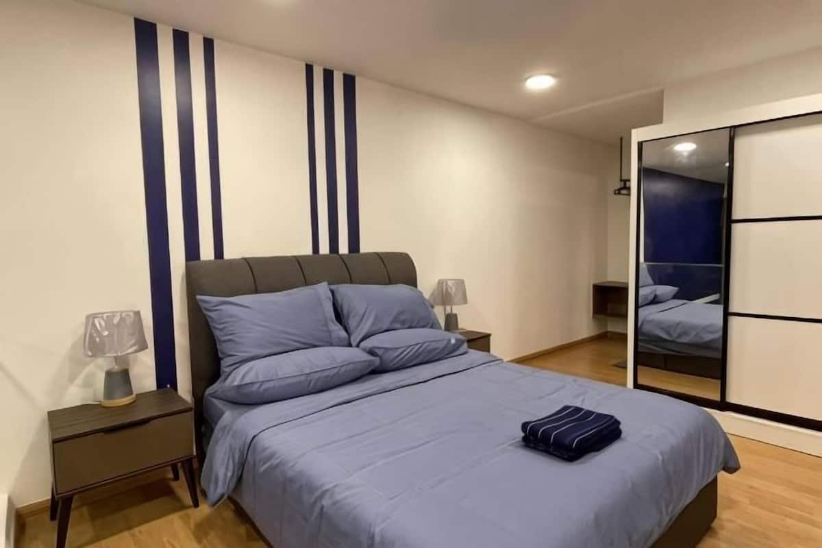 A bedroom with a bed, nightstands, a mirror, and a wardrobe.