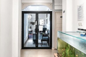 A reception area with a glass partition, a reception desk, and a fish tank. - Rays Residence (Jakarta)