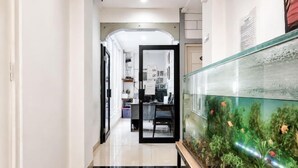 A hallway with a fish tank, a desk, and a chair in the background. - Rays Residence (Jakarta)
