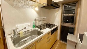 A compact kitchen with a sink, stove, and cabinets. - SunStay Fudomae I（601） (Tokyo)