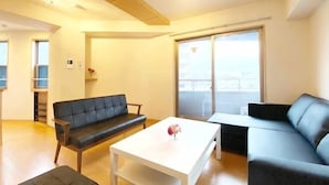 A modern living room with a sofa, a coffee table, and a large window. - SunStay Fudomae I（601） (Tokyo)