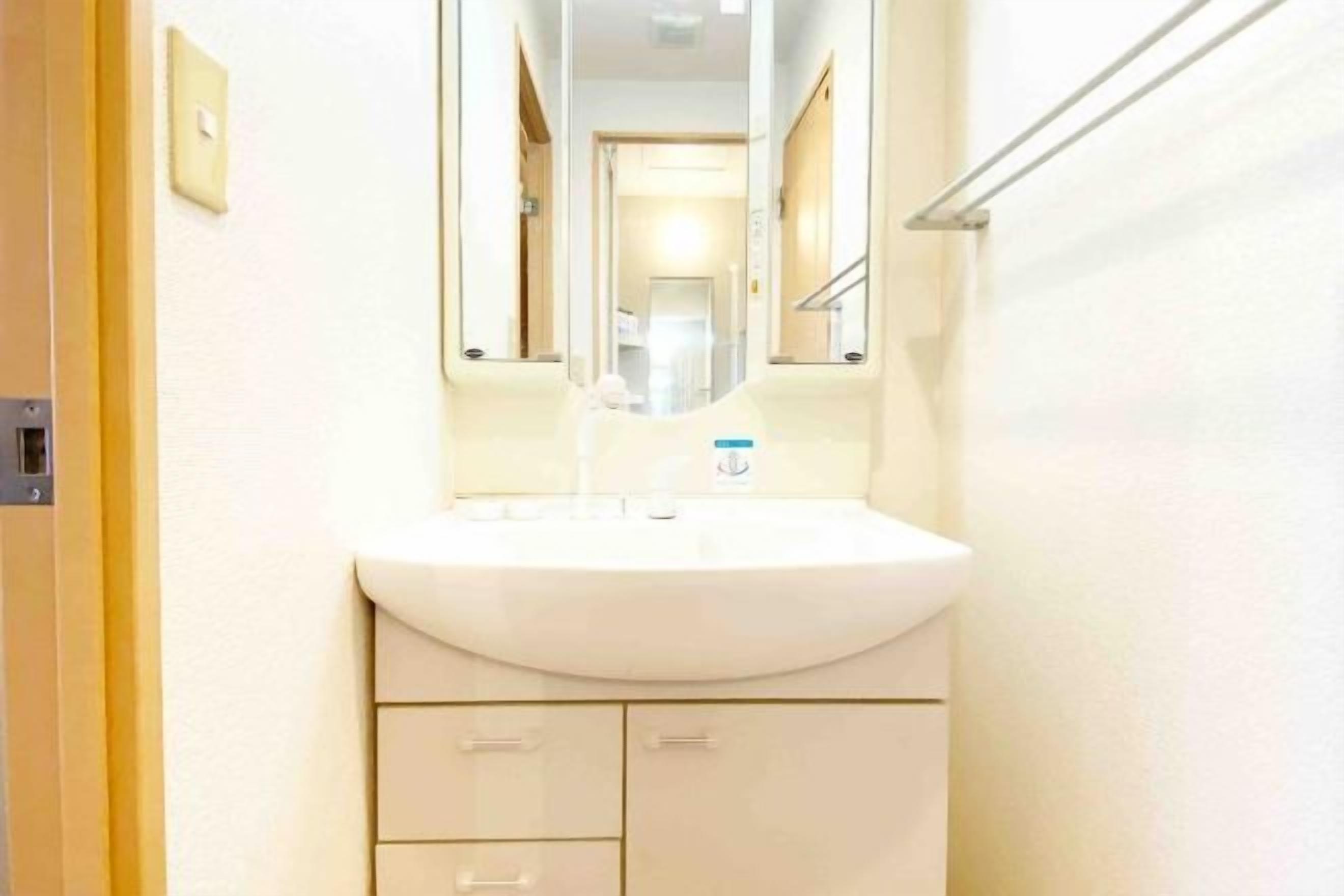 A bathroom with a white sink, a mirror, and a towel rack.