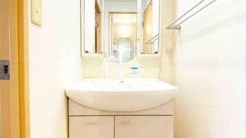 A bathroom with a white sink, a mirror, and a towel rack.