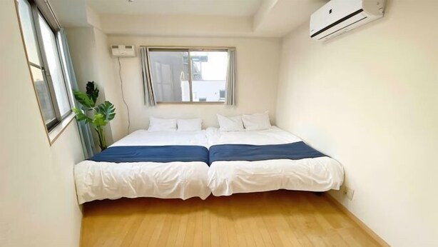A room with a double bed, a window, and an air conditioning unit. - SunStay Fudomae I（601） (Tokyo)