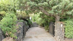 A pathway leading through a garden with stone walls and dense foliage. - Private Villa Izu Omuro Kogen (Ito)