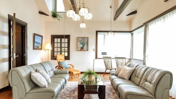 A living room with two sofas, a coffee table, and a chandelier. - Private Villa Izu Omuro Kogen (Ito)