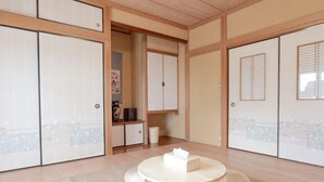 A traditional Japanese room with sliding doors, a round table, and tatami mats. - Private Villa Izu Omuro Kogen (Ito)