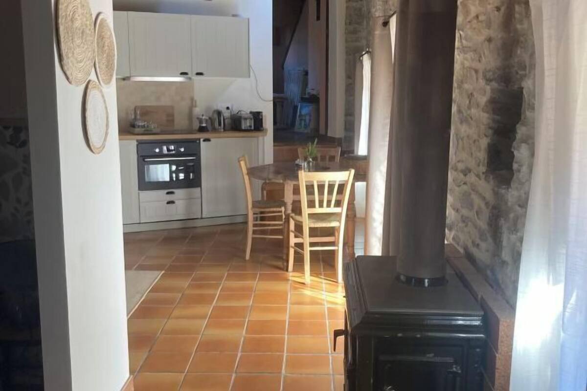 A kitchen with a stove, cabinets, and a dining area with chairs.