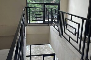 A multi-level interior with a metal railing and a tiled floor. - RedDoorz at Greenhouse Tegalwaras Palagan (Ngaglik)