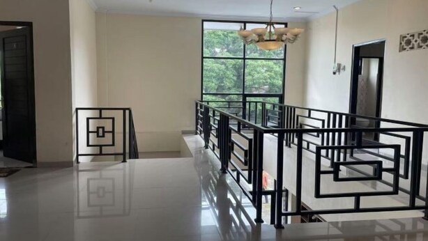 Um quarto espaçoso com uma grande janela, guarda-corpo de metal preto e um candelabro.