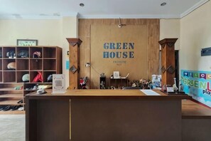 A reception desk with a wooden backdrop and the words 'GREEN HOUSE' prominently displayed. - RedDoorz at Greenhouse Tegalwaras Palagan (Ngaglik)