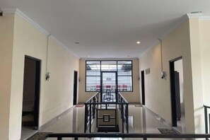 Un couloir se termine par une porte en verre, qui donne sur un escalier.