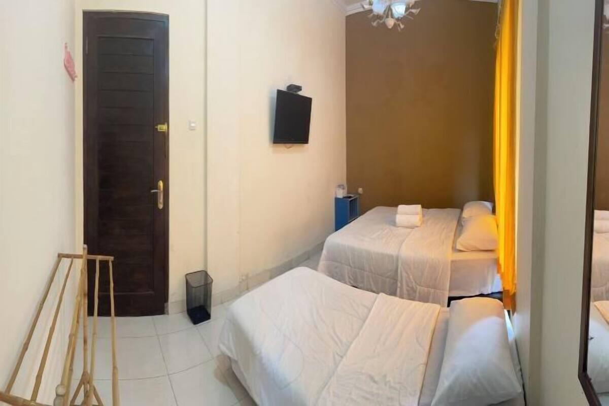 A room with two beds, a door, a television, and a mirror.