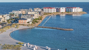 A coastal area with beachside cottages, a rocky breakwater, and modern buildings along the shore. - Gorgeous apartment in OstseeResort Olpenitz (OstseeResort Olpenitz)
