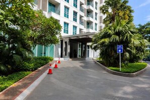 L’entrée d’un hôtel, avec une allée couverte, des palmiers et une enseigne bleue.