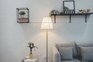 A modern living room with a grey sofa, a floor lamp, and a small table with a vase of flowers. - D Wah Retreat Botanika 3BR 8pax Mahjong table (Plentong)