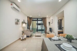 A modern living room with a sofa, a coffee table, and a dining area with a table set for two. - D Wah Retreat Botanika 3BR 8pax Mahjong table (Plentong)