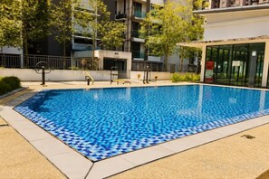 A rectangular swimming pool with a tiled edge, surrounded by a paved area, with a building in the background. - D Wah Retreat Botanika 3BR 8pax Mahjong table (Plentong)