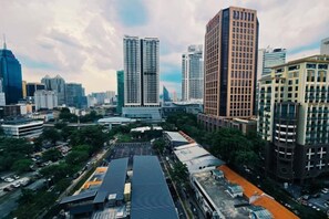 A cityscape with high-rise buildings, a parking lot, and a large open area with a building in the foreground. - Anggun KLCC 1BR @KL City monorail Netflix 1CP (Kuala Lumpur)