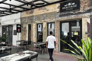 An outdoor seating area with tables and chairs, a sign for 'Heritage Pizza,' and a brick building facade. - Anggun KLCC 1BR @KL City monorail Netflix 1CP (Kuala Lumpur)