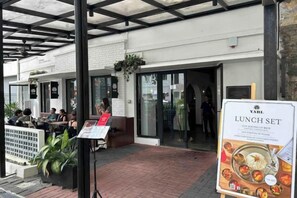 An outdoor seating area with tables and chairs, a menu stand, and a building entrance. - Anggun KLCC 1BR @KL City monorail Netflix 1CP (Kuala Lumpur)