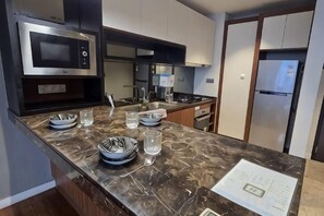 Una cocina moderna con encimera de mármol, electrodomésticos de acero inoxidable y horno empotrado.