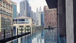 A modern hotel with a reflective pool, high-rise buildings, and a view of the Petronas Towers. - Anggun KLCC 1BR @KL City monorail Netflix 1CP (Kuala Lumpur)
