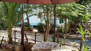 A patio area with a mosaic-tiled table and seating, surrounded by potted plants and trees. - Baan Namthip Homestay Trang บ้านน้าทิพย์ โฮมสเตย์ตรัง (Sikao)