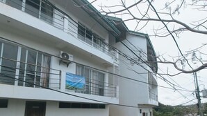 A multi-story building with a balcony, a staircase, and a banner. - RedDoorz @ Garvs Boutique Hotel Boracay (Boracay Island)