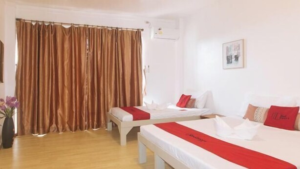A hotel room with two beds, a curtain, a wall-mounted air conditioner, and a framed picture. - RedDoorz @ Garvs Boutique Hotel Boracay (Boracay Island)