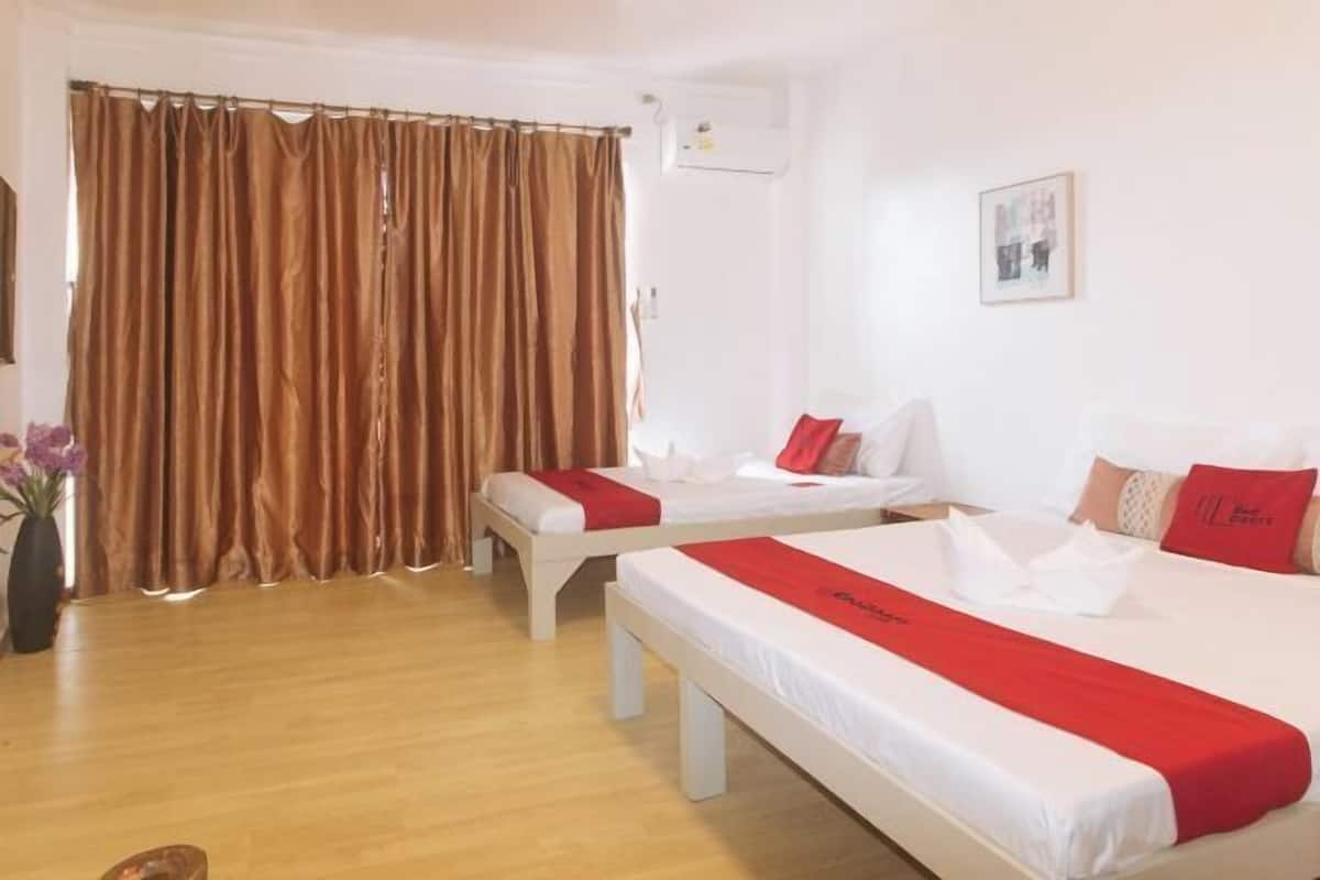 Ein Hotelzimmer mit zwei Betten, einem Vorhang, einer Wand-Klimaanlage und einem gerahmten Bild.