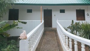 A corridor with a white balustrade, a wooden door, and potted plants. - RedDoorz @ Garvs Boutique Hotel Boracay (Boracay Island)