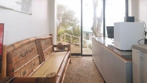 A room with a wooden bench, a white desk with a computer, and a large window with a view of greenery. - RedDoorz @ Garvs Boutique Hotel Boracay (Boracay Island)