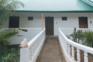 A building with a covered walkway, white walls, and a green roof. - RedDoorz @ Garvs Boutique Hotel Boracay (Boracay Island)