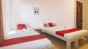 Two single beds with white bedding and red accents, a small bedside table, and a door to the right. - RedDoorz @ Garvs Boutique Hotel Boracay (Boracay Island)