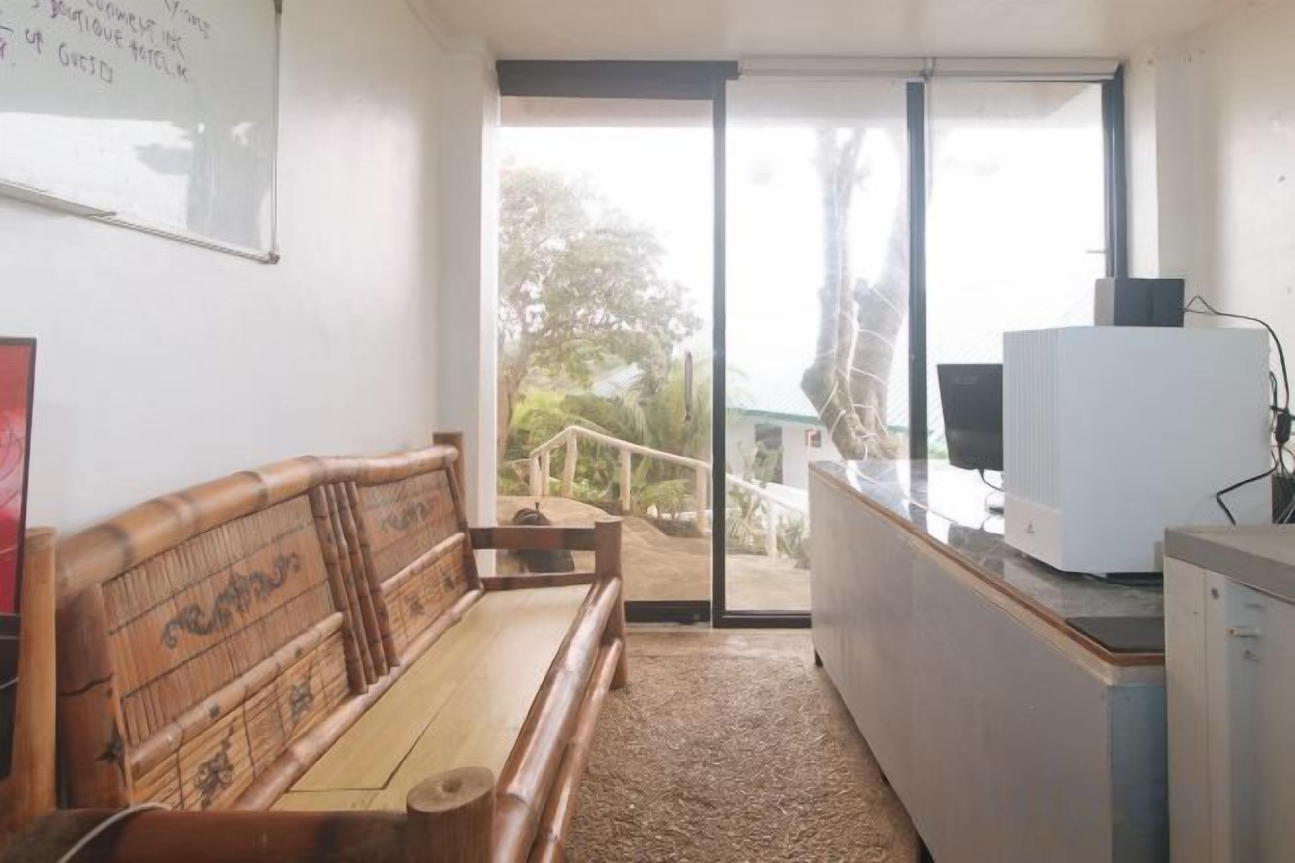 Una habitación con un banco de madera, un escritorio con computadora y vista a través de un vidrio.