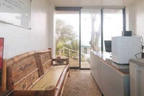 A room with a wooden bench, a desk with a computer, and a view through a glass door. - RedDoorz @ Garvs Boutique Hotel Boracay (Boracay Island)